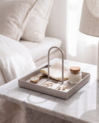 Zivol Arc square warm grey tray with jewellery on a marble bedside table