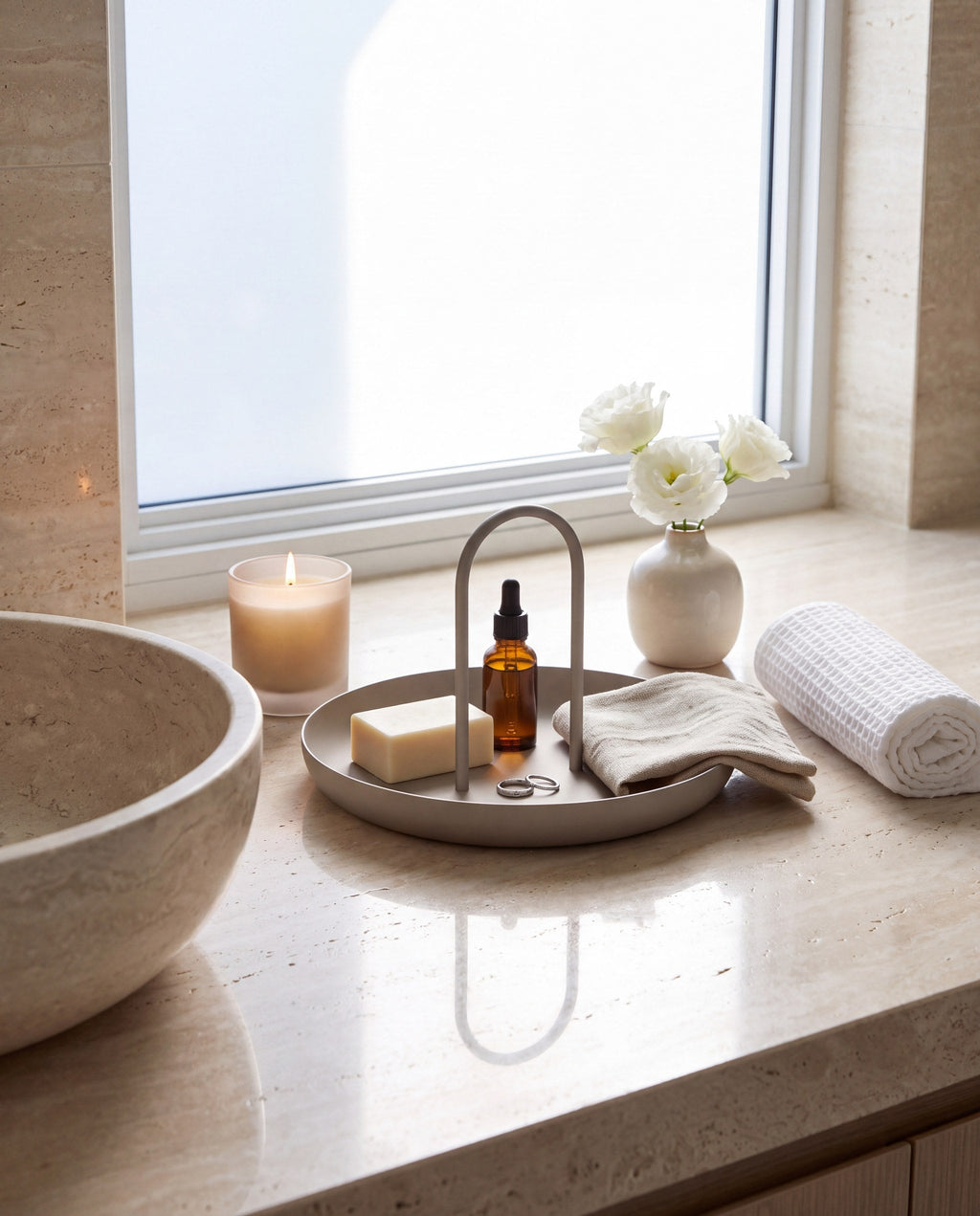 Zivol Arc warm grey tray with soap and face oil on a travertine bathroom counter