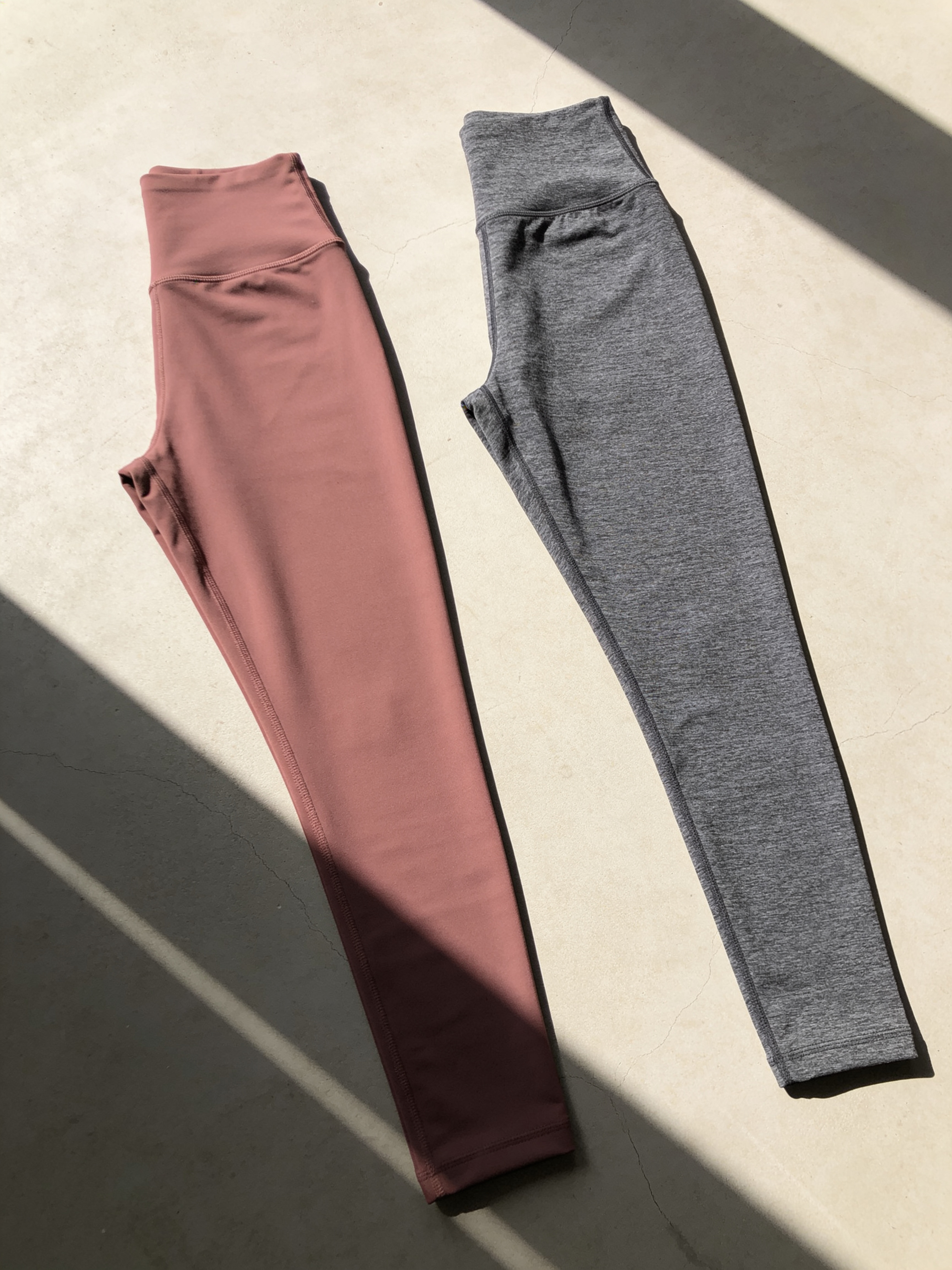 Pink and grey Zivol Claim leggings laid flat side by side, both with the handprint print