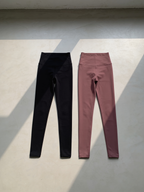 Black and pink Zivol Claim leggings laid flat side by side, both with the handprint print