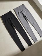 Black and grey Zivol Claim leggings laid flat side by side, both with the handprint print