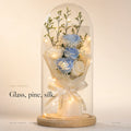 Zivol Ember everlasting rose in a tall glass dome on a pale wood base